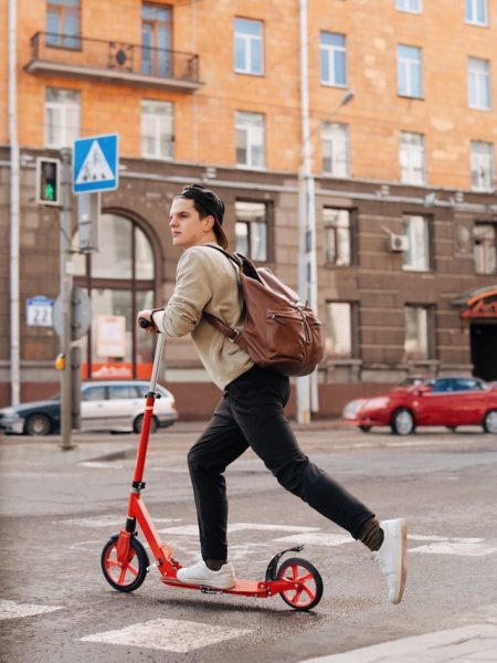 A man riding a kick scooter in the city. Scooter is a fun and easy way to explore the streets. Also, scooters are cheap and easy to ride. It is important to get the right scooter size for you for a comfortable scooter ride. Get the right scooter size for your needs and get into scooter lifestyle.