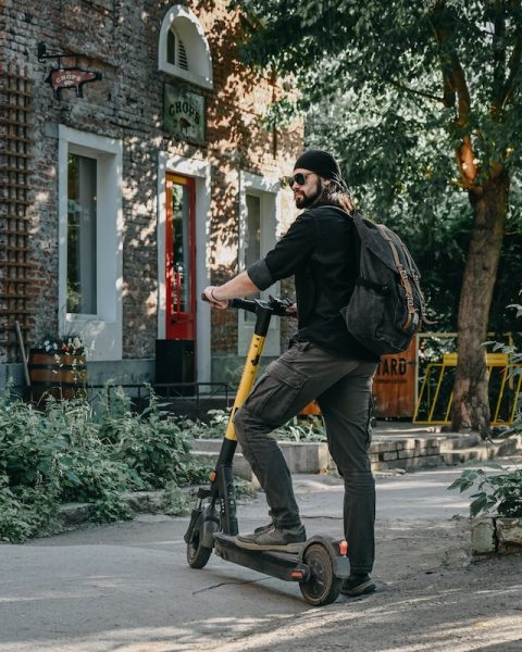 A man riding scooter in style. A man riding a scooter. Scooter provides fun and easy way to get from point A to point B. Make sure to get the right size of scooter for a comfy ride.