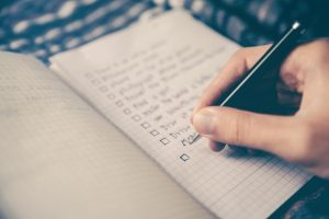 A person creating a maintenance checklist on the notebook.