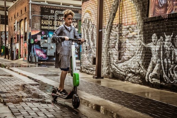 Young boy riding riding an e-scooter down the street.