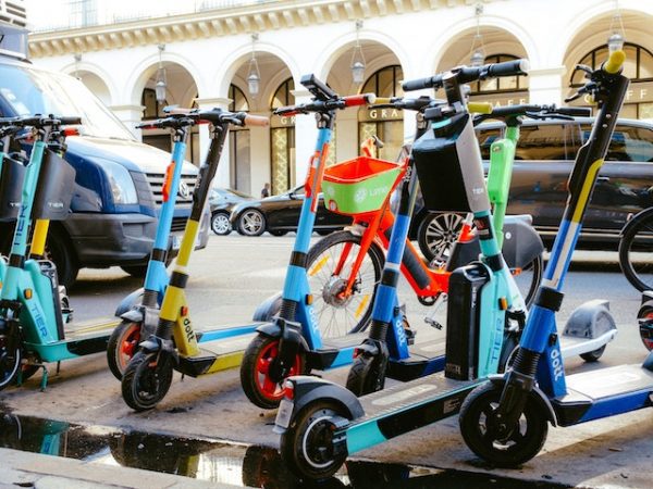 Colorful and compact rechargeable scooters parked on the side of the road.