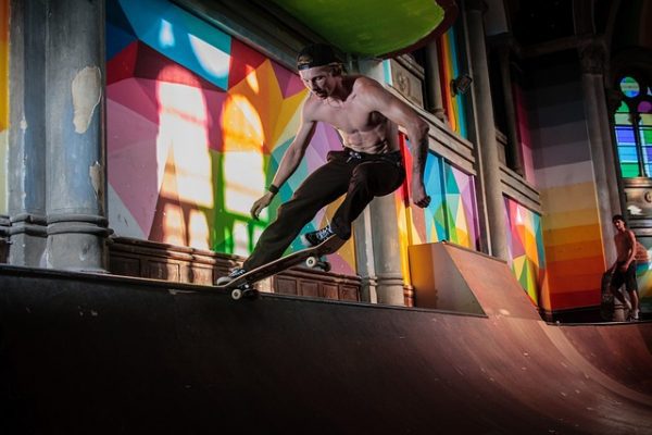 A topless guy is using a trick skateboard 