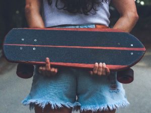Woman with denim shorts holds a cruiser board.
