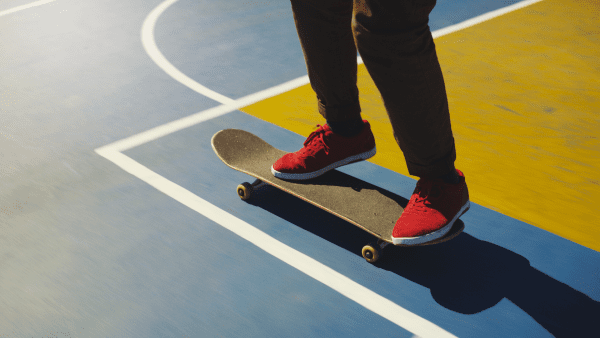 riding a skateboard in the basketball court trying to practice tricks