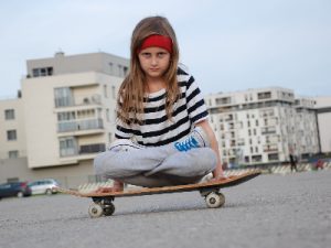 a young girl sitting on a kids' skateboard