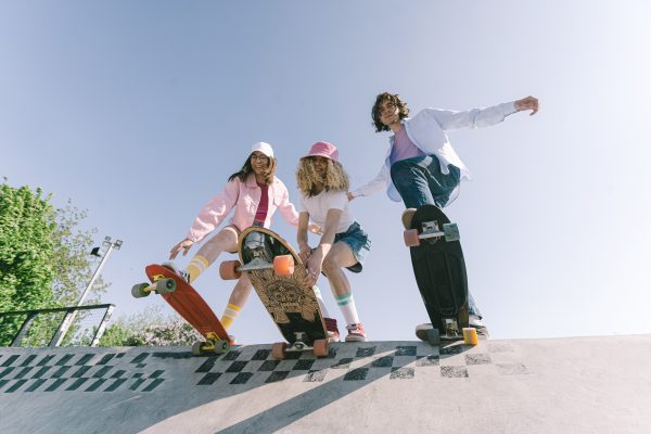 Three ladies are about to do skateboarding