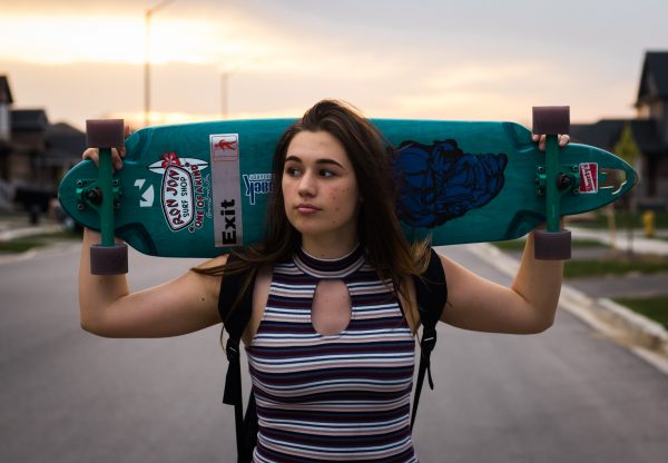 The girl is carrying her Skateboard