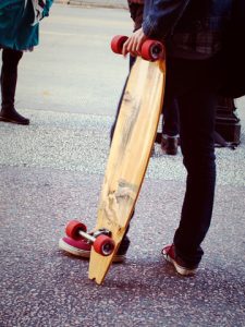 A person standing holding a longboard.