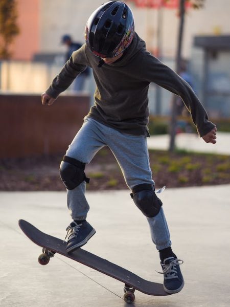 Skateboarding Pads: A young skateboarder doing tricks on his skateboard while wearing a helmet and knee pads. Wearing protective skate padding and skate gear is crucial when practicing skateboard tricks. Choose high-quality skate gear to keep yourself safe and protected on your skateboard.