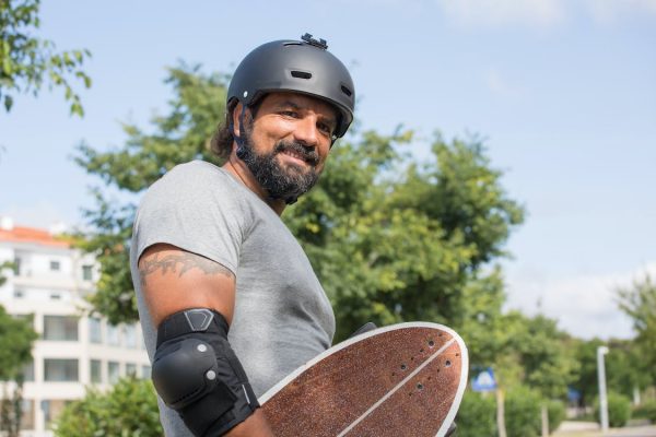 A skateboarder carrying a skateboard while wearing the appropriate skate gear. Even if you're just skating casually, skateboard helmets are essential skate gear and must not be overlooked. Skateboard helmets may not be the most glamorous part of your skate gear, but they can definitely be a lifesaver while skating.