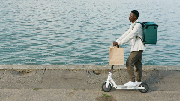 The guy is riding his scooter near the ocean