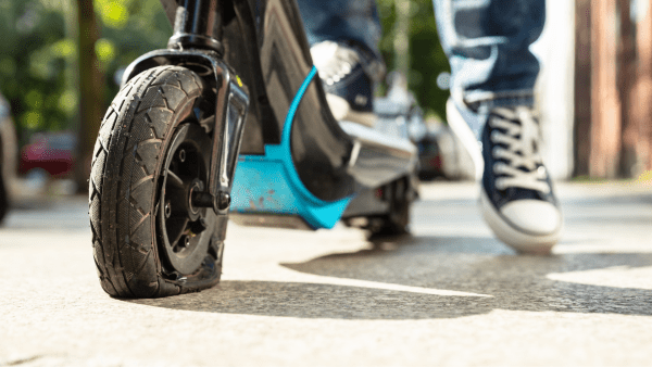 Flat wheeled scooter with a rider wearing a shoe. 