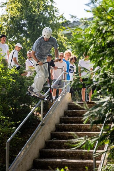 A man in a helmet doing tricks on outdoor railings while people watch