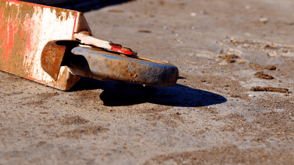 A color blue wheel on the ground covered with thick dirt and rust. 