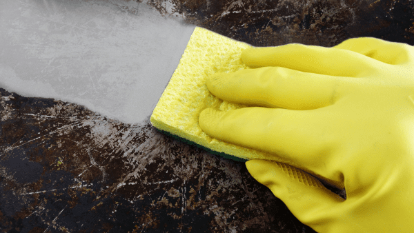 A hand holding a sponge that removes surface dirt