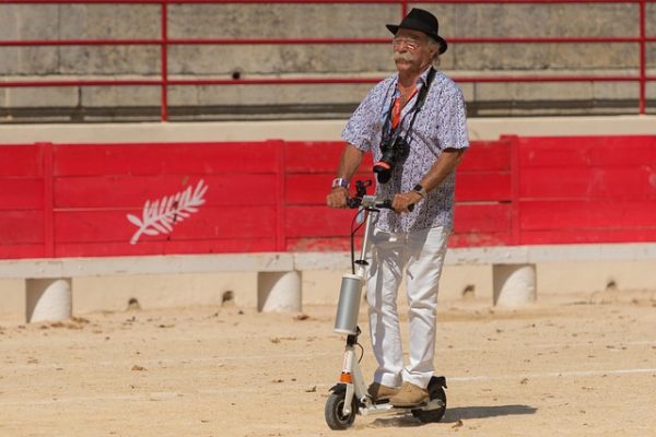 old man riding his scooter in sand enjoying his time