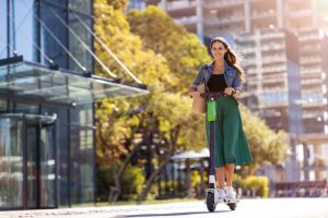 A confident woman gracefully navigates the city streets, effortlessly weaving through the empty street in the city. Her wind-blown hair and joyful smile reflect the freedom and convenience this mode of transportation offers in her bustling urban life.