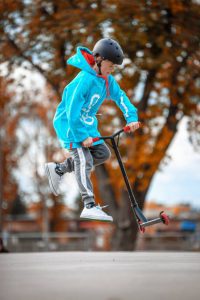 A child doing jump tricks on his scooter