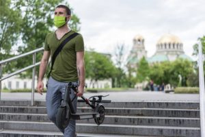 a man is carrying his collapsible scooter after a long day at work or a long day commuting, best finds so far!