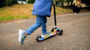 A happy kid kicking her scooter to have fun.