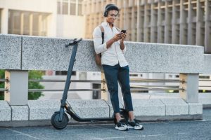 best ride that young adults can use, this man is standing next his ride. It is equipped with front and rear disc brakes or responsive drum brakes offer reliable breaking power, reducing the risk of accidents and ensuring smooth, controlled rides.