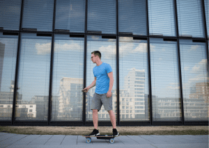 This man is using an electric skateboard. 