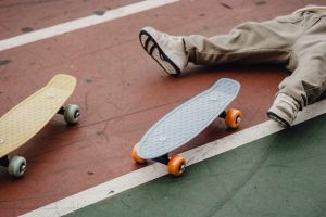 Skateboard Reviews: A skateboard rider lying on the ground with a skateboard beside his feet, tired of skateboarding. 