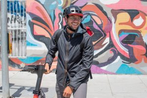 scooter safety features - Smiling man with a helmet on his scooters.