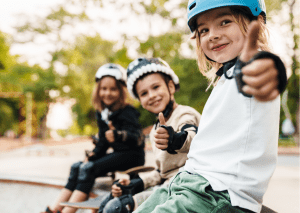 Children wearing helmets giving thumbs up.