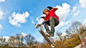 A boy effortlessly performs an impressive scooter flair trick on his trusty scooter. His flawless execution and fearless spirit showcase the artistry of mastering this thrilling scooter maneuver, capturing the essence of scooter excitement.