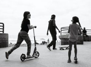 Three young kids on kick scooters are having fun.