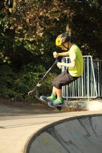 A young child tricks on a scooter.