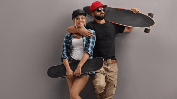 A couple holding their skateboards 
