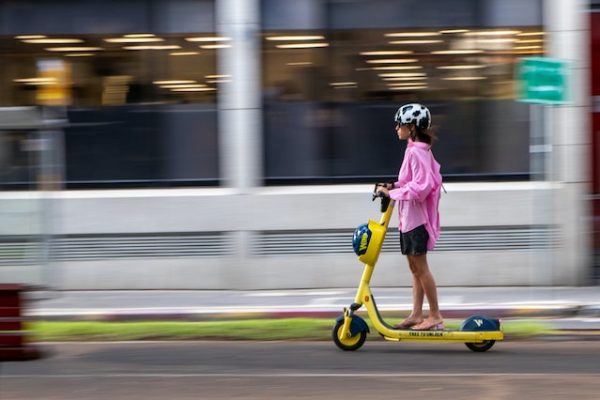 A woman in pink riding an electric scooter.