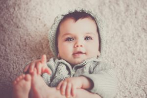 A cute baby baby girl play with her toes and legs