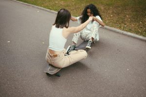 Two skaters holding hands while sitting on their skateboards