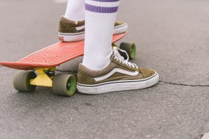 A person with socks rides his orange skateboard