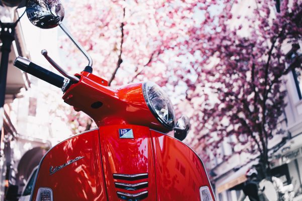 A well-maintained scooter, parked around a beautiful neighborhood.