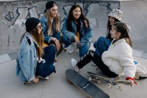Five female skateboarders with boards chat with each other while resting. 