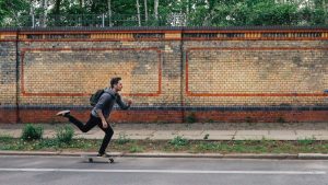 A man is happily skateboarding on the street, enjoying a clean surrounding