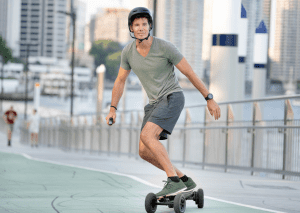 Man riding a skateboard down the street. A man is very happy trying to make his way to through the city. Way to go!