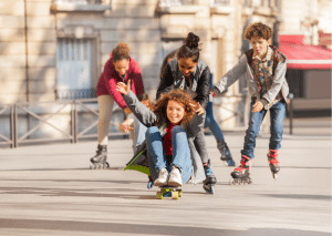 girl on a skateboard while 3 other friends roller skate