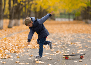 A kid wearing blue jacket practices proper falling technique for safety skateboard riding. 