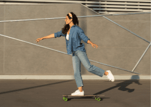 A woman with a blue shirt rides her off-road skateboard confidently. 