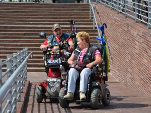 Two people riding mobility scooters with a basket