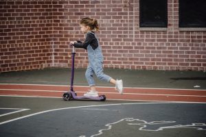 A young kid who is scooting at the court.