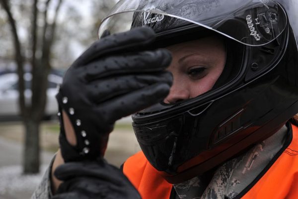 A woman is wearing protective gear as she is about to ride her scooter.