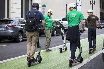 Four men with helmet are riding a scooter.