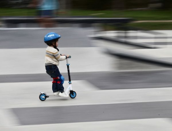 A boy with blue helmet is riding his moped.