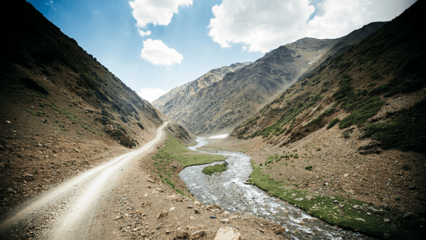 Different Terrains. There are mountains mostly filled with solid rocks and soil. There is a road and a river in the middle. 